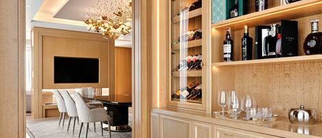 A modern interior with a wooden cabinet displaying various bottles and glasses, a dining area with a TV, and a chandelier.