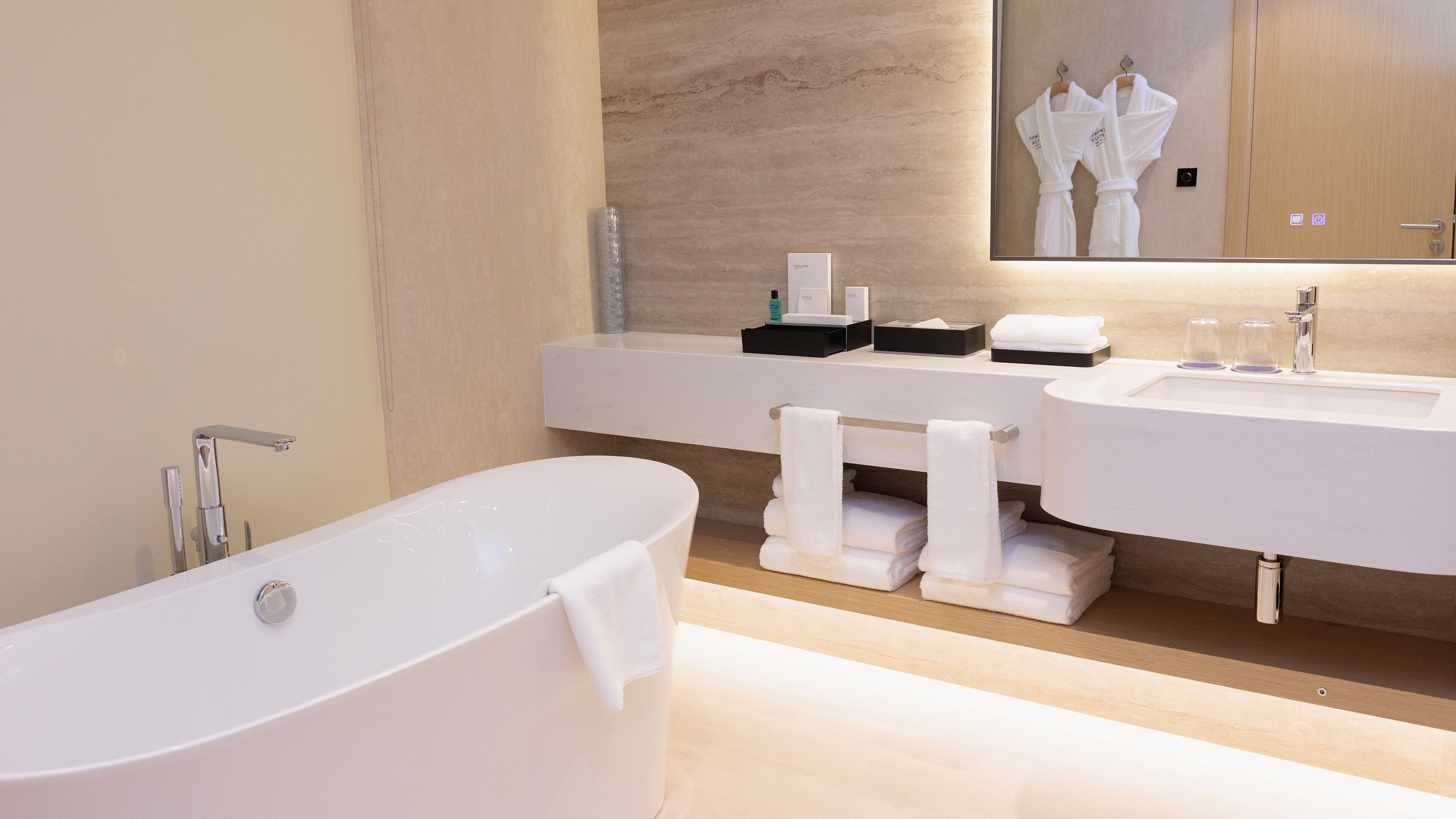 Un baño moderno con una bañera independiente, dos lavamanos y un espejo grande.
