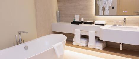 Un baño moderno con una bañera independiente, dos lavamanos y un espejo grande.