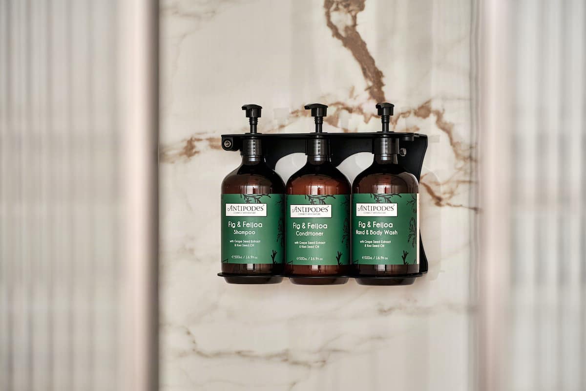 Three bottles of Antipodes products on a marble wall.