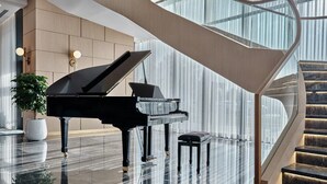 A grand piano in a spacious, modern lobby with a marble floor and a curved staircase. - Crowne Plaza Dushanbe by IHG (Dushanbe)