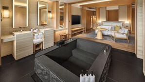 Una habitación de hotel moderna con una bañera grande, un sofá y un televisor.