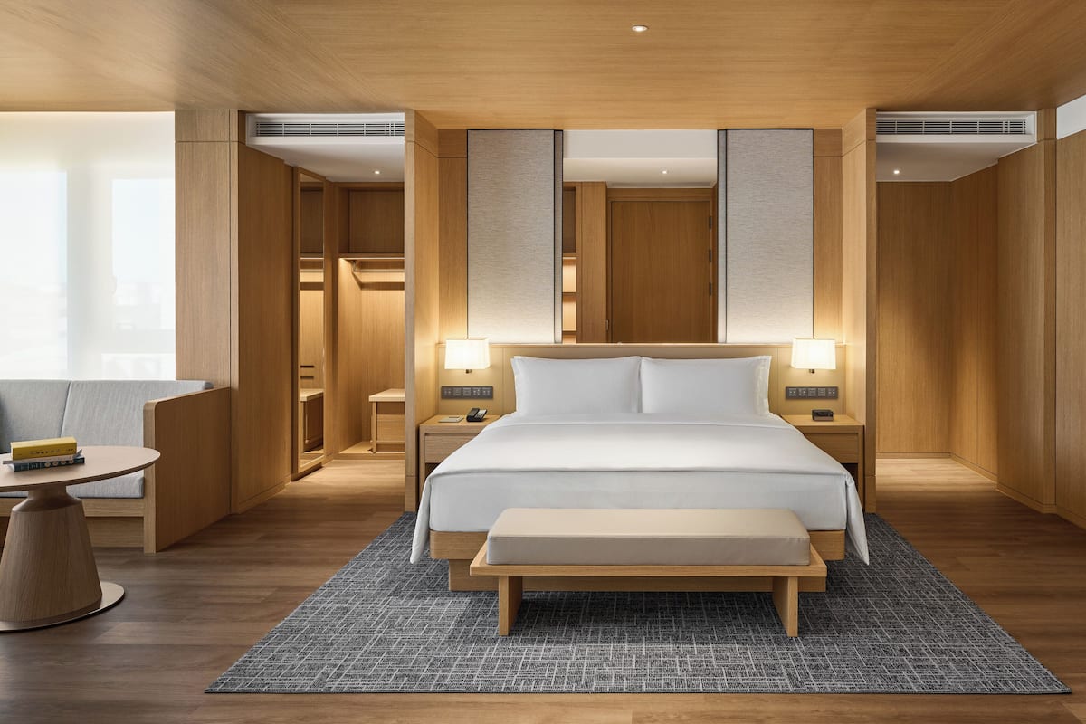 Une chambre d’hôtel moderne avec un grand lit, des lampes de chevet, un petit bureau et une table de chevet.