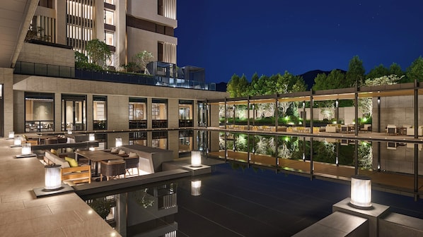 A modern outdoor pool area with seating and a restaurant.