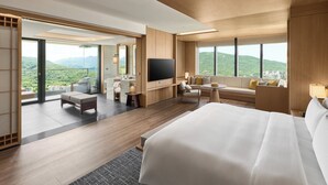A hotel room with a large bed, a TV, a sofa, a desk, and a balcony with a view of the mountains. - Intercontinental New Taipei Hot Spring by IHG (New Taipei City)