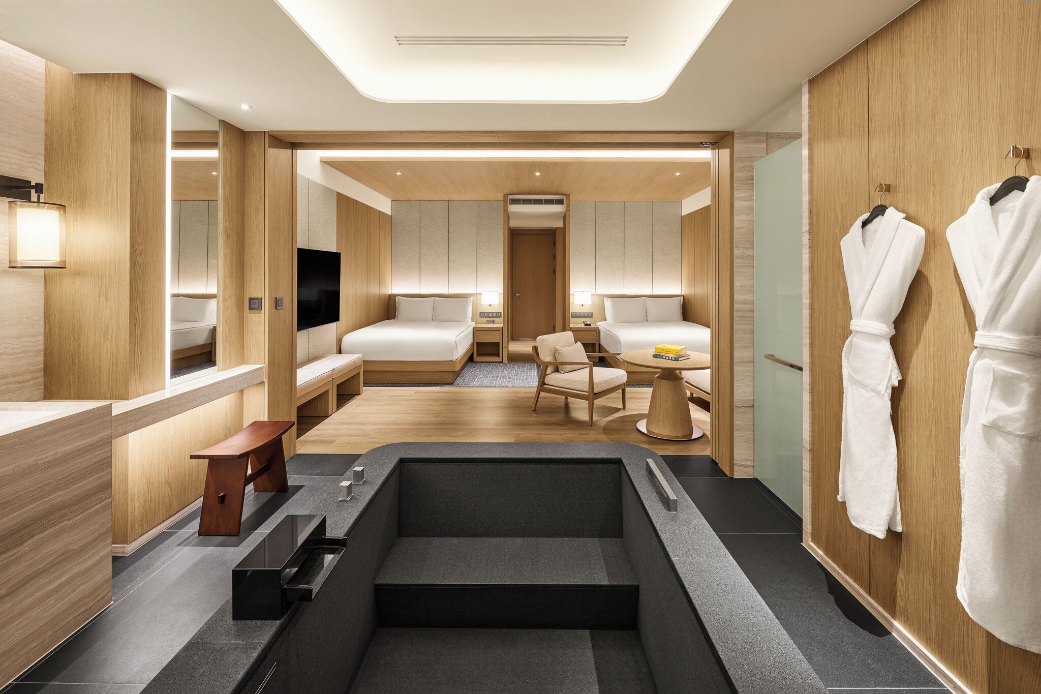 A modern hotel room with a large bathtub, a desk, and a seating area.