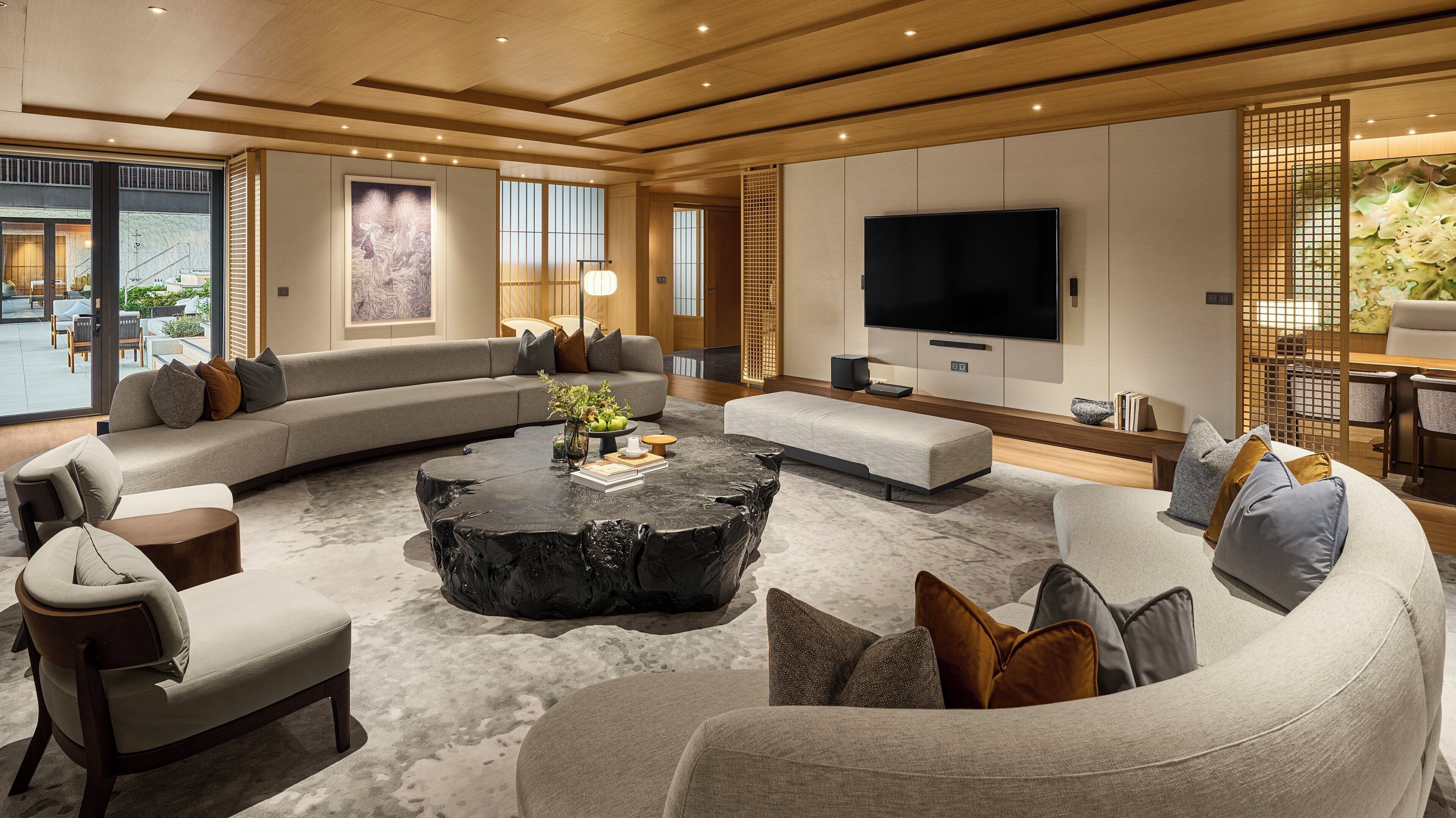 A modern living room with a sectional sofa, a round coffee table, and a large flat-screen TV.