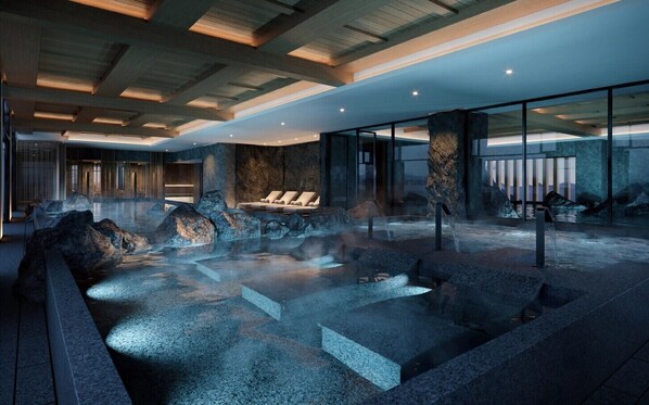 Ein moderner Wellnessbereich mit Thermalquelle, Sitzgelegenheiten und einer Steinwand.