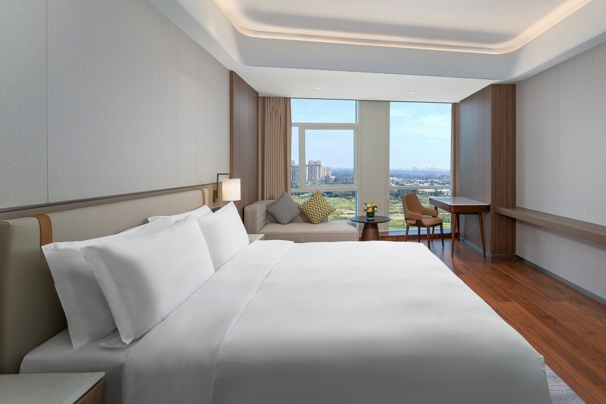 Una habitación de hotel con una cama grande, un escritorio, una silla y un televisor.