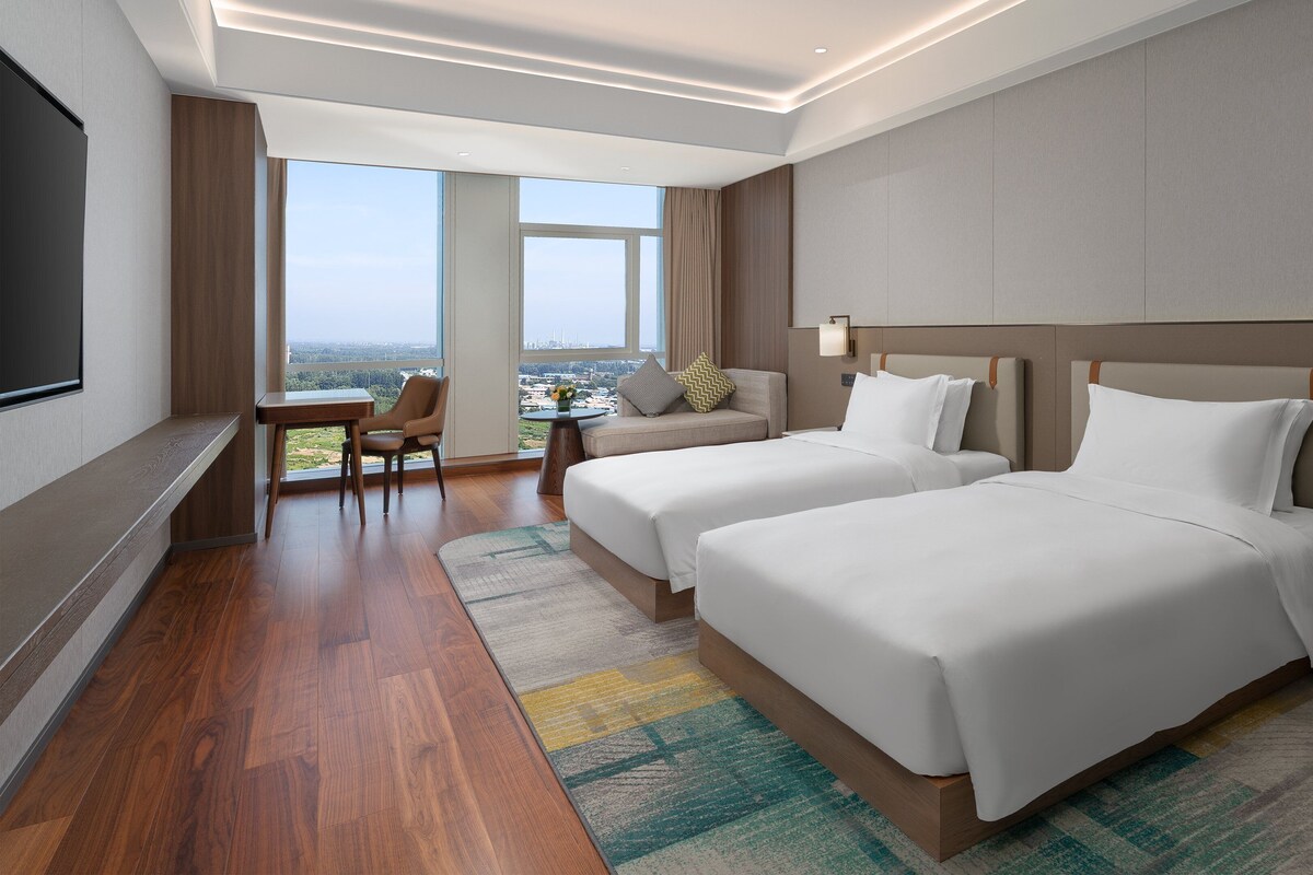 Habitación de hotel con dos camas, un escritorio y una silla.