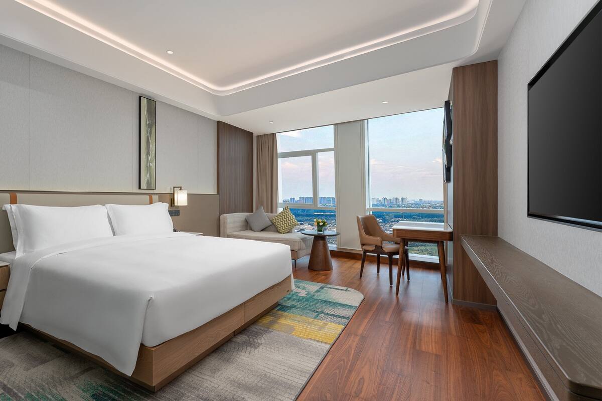 Een moderne hotelkamer met een groot bed, nachtkastjes, een bureau en een televisie.