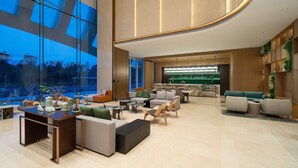 A modern hotel lobby with a large glass wall, seating areas, a reception desk, and a bar. - Holiday Inn Xingtai Quancheng by IHG (Xingtai)