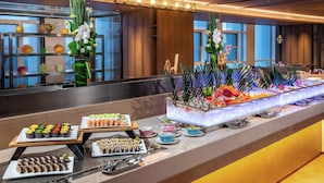 A buffet with various sushi dishes, a seafood display, and decorative flowers. - Holiday Inn Xingtai Quancheng by IHG (Xingtai)