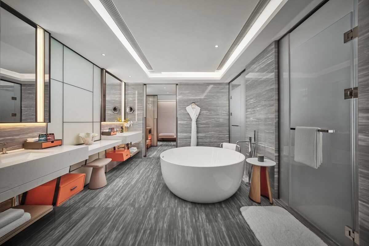 A modern bathroom with a large bathtub, a vanity with a mirror, and a shower area.