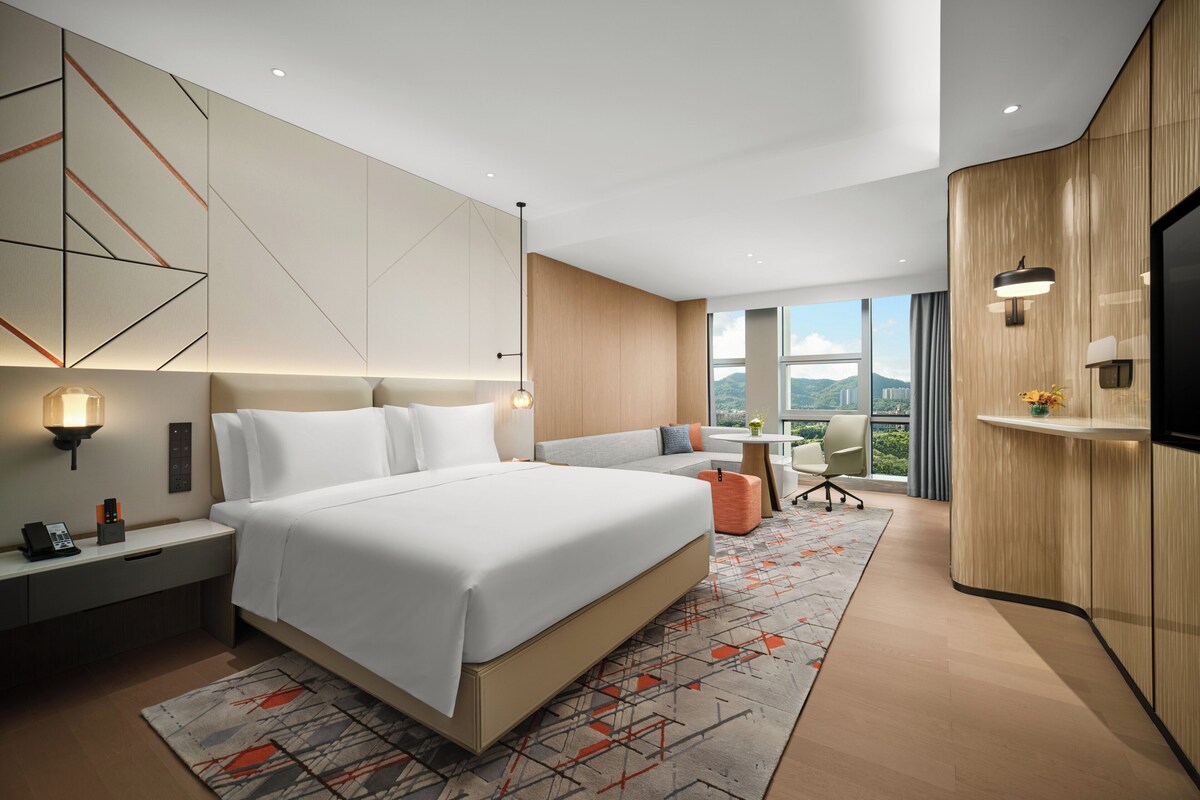 A modern hotel room with a large bed, a desk, and a TV.