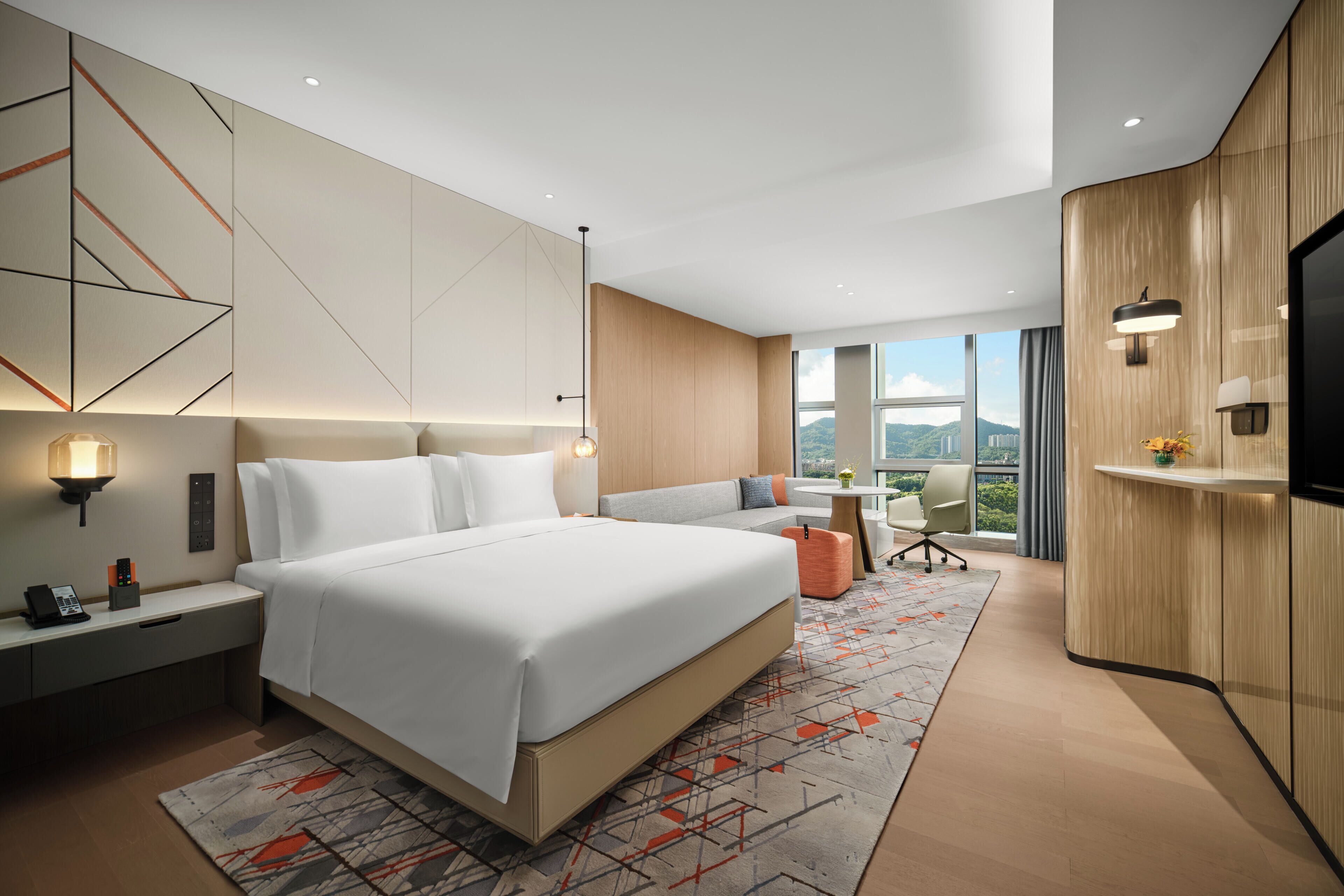Une chambre d’hôtel moderne équipée d’un grand lit, de tables de chevet, d’un bureau, d’une chaise et d’un téléviseur.