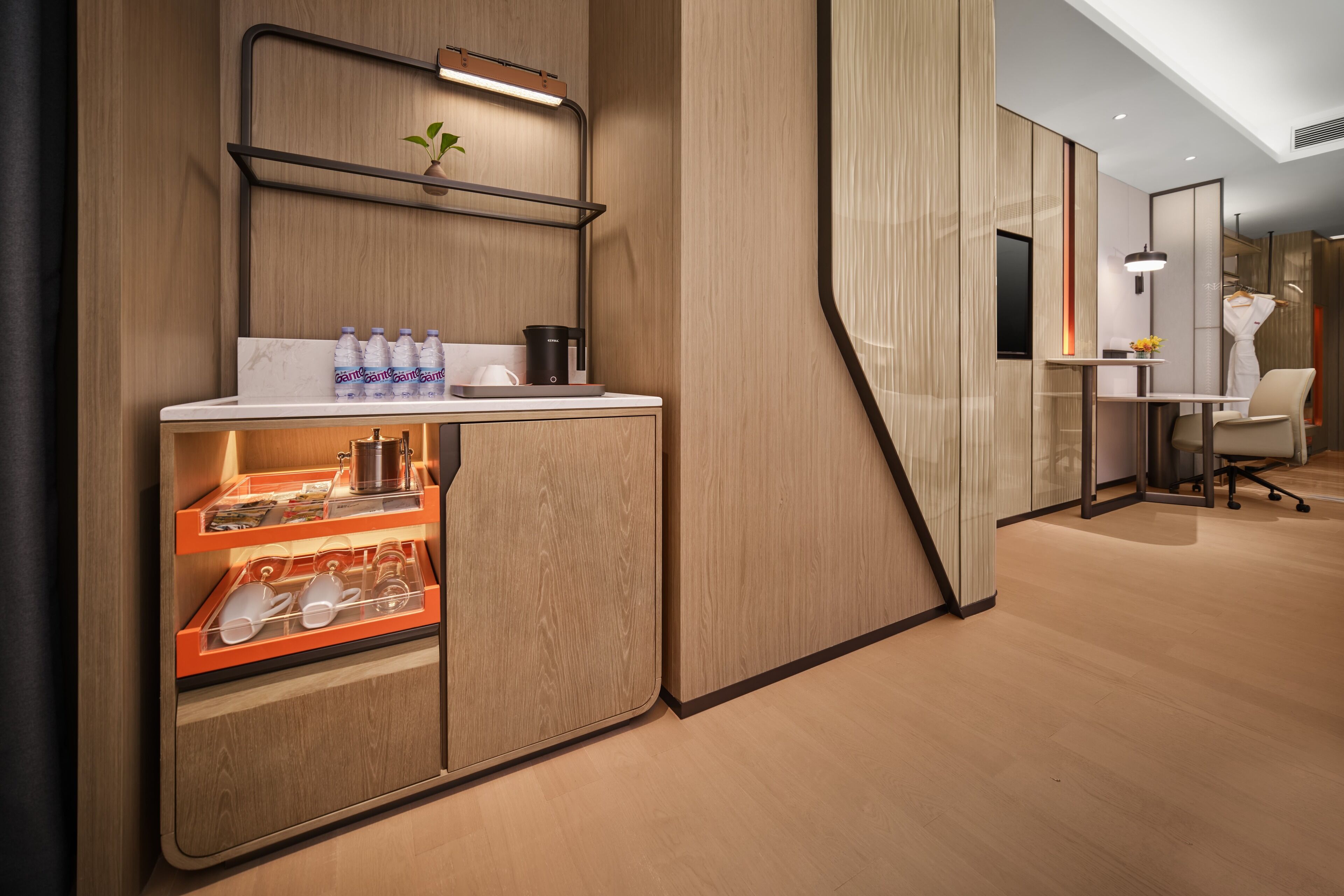 Una habitación de hotel moderna con un aparador de madera, una mesita con una planta y un escritorio con una silla.