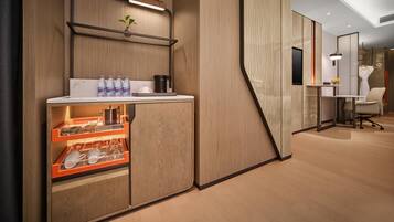 Una habitación de hotel moderna con un aparador de madera, una mesita con una planta y un escritorio con una silla.