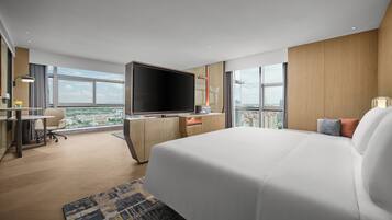 Una habitación de hotel moderna con una cama grande, un televisor de pantalla plana, un escritorio con silla y vistas a la ciudad.