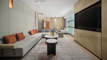 A modern living room with a sectional sofa, a round coffee table, and a large flat-screen TV mounted on the wall.