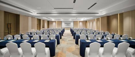 A conference room with rows of tables and chairs, equipped with water bottles and nameplates.