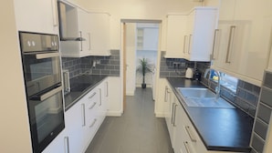 A modern kitchen with white cabinets, black countertops, and a black oven.