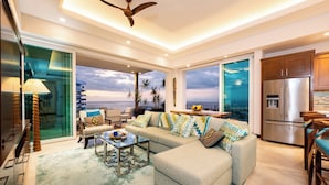 A modern living room with a sofa, coffee table, and a view of the ocean.