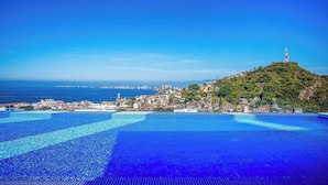 A coastal town with a prominent hill, a tower, and a large swimming pool.