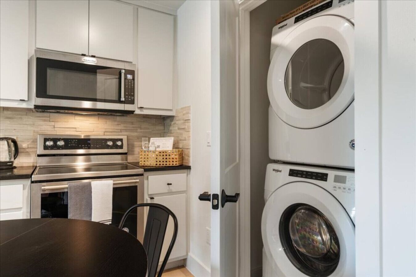A compact kitchen with a microwave, oven, and stacked washer-dryer unit.