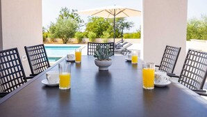 Una mesa de comedor con sillas, una planta en maceta y vasos de jugo de naranja.