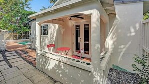 A white building with a covered patio area, a pool, and a small table with chairs. - LUXTROPICA (Miami)