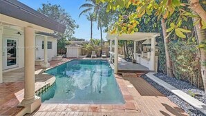A swimming pool with a pergola and palm trees in the background. - LUXTROPICA (Miami)