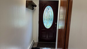 Un couloir avec une porte en bois, un vitrail et un tapis coloré.