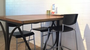 A dining area with a wooden table and four black chairs with metal frames. There are two wall-mounted paintings above the table. - Sweet home nearby UOA (Tucson)