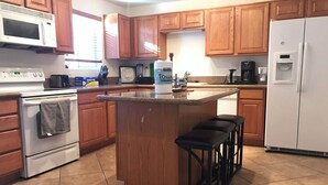A kitchen with wooden cabinets, a white refrigerator, a microwave, a stove, and a coffee maker. - Sweet home nearby UOA (Tucson)