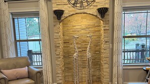 Un salón con pared de piedra, un reloj grande y dos esculturas de jirafa.