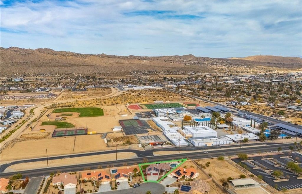 An aerial view of a commercial area with parking lots, buildings, and a sports field.