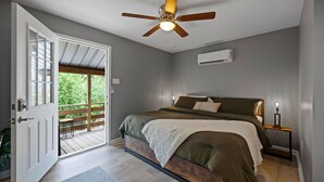 Een slaapkamer met een bed, een plafondventilator, een airconditioning en uitzicht op de omgeving.