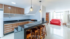A modern kitchen with wooden cabinets, a black countertop, and a red sofa in the living area.