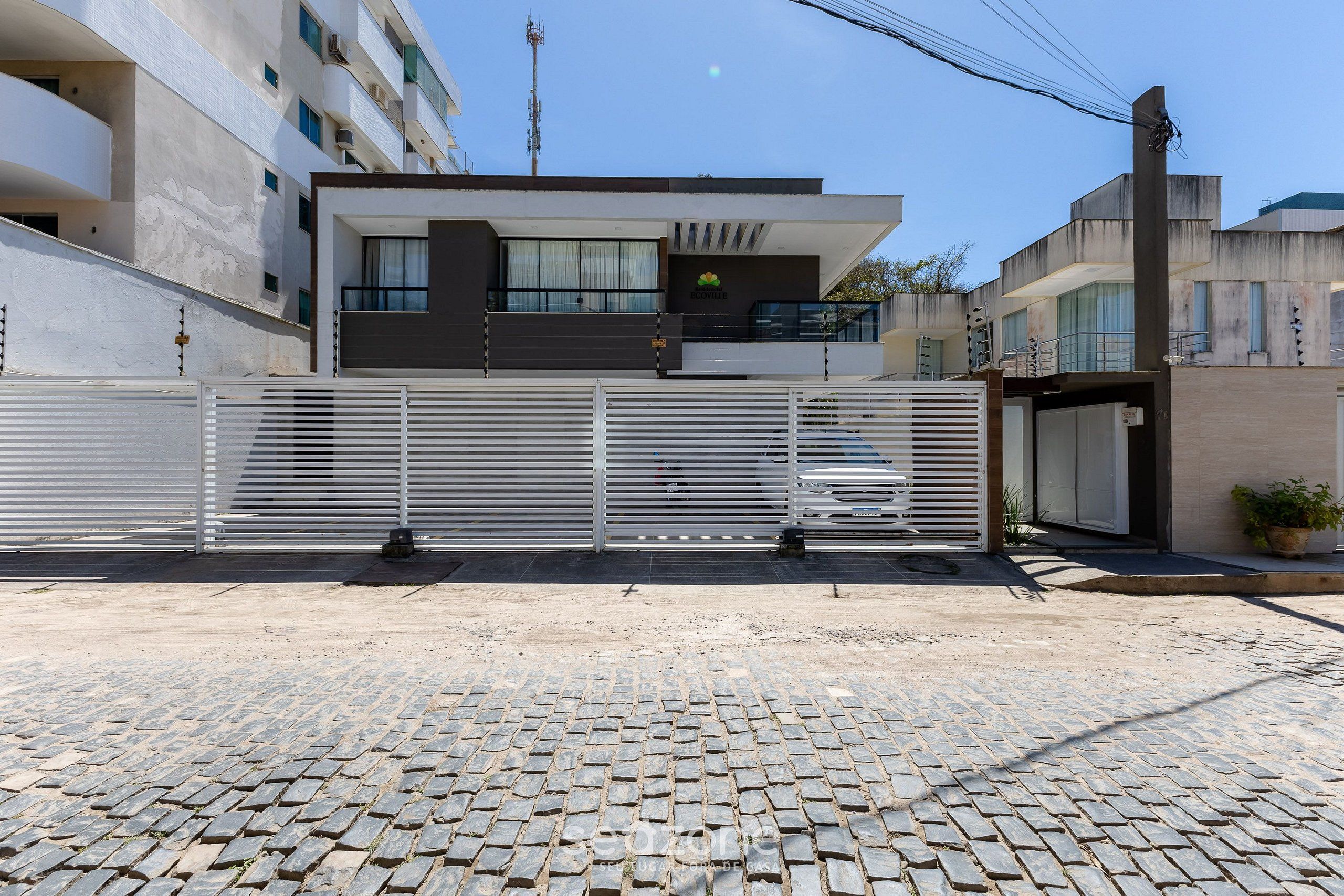 Un edificio moderno con entrada porticada, camino de entrada pavimentado y calle adoquinada.