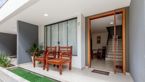 A modern entrance with two wooden chairs, a glass door, and a staircase leading inside.