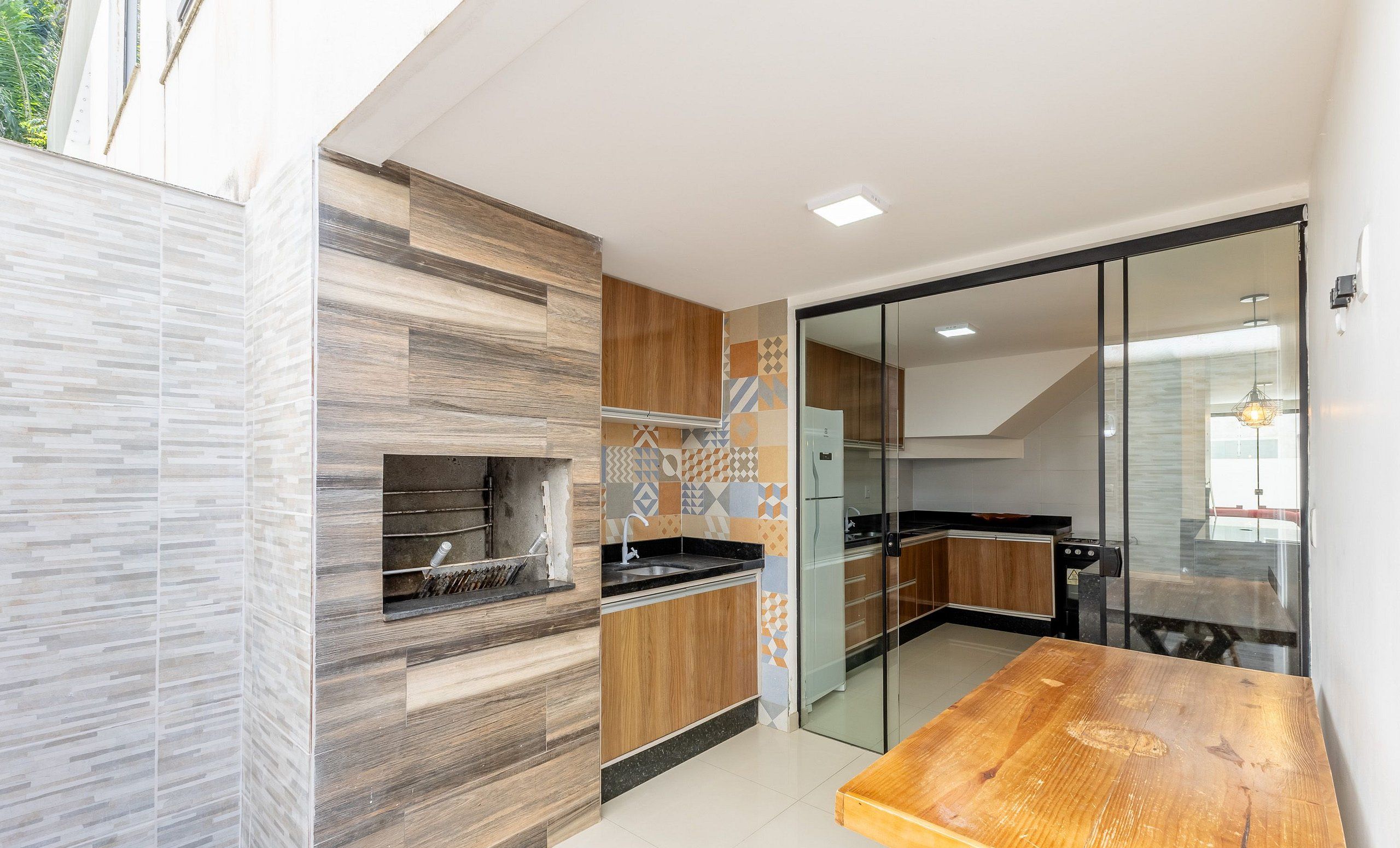 A modern kitchen with a built-in oven, wooden cabinets, and a glass door leading to a dining area.