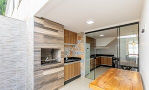 A modern kitchen with a built-in oven, wooden cabinets, and a glass door leading to a dining area. - House w/ Terrace & BBQ 100m From the sea Ellc0000 (Ilhéus)