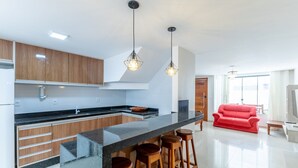 Una cocina moderna con armarios de madera, encimera negra y sofá rojo en la sala de estar.