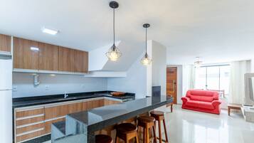Uma cozinha moderna com armários de madeira, bancada preta e sofá vermelho na sala de estar.