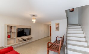 A modern living room with a flat-screen TV, a wooden bench, and a staircase. - House w/ Terrace & BBQ 100m From the sea Ellc0000 (Ilhéus)