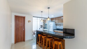 Una cocina moderna con encimera negra, taburetes de madera e iluminación colgante.
