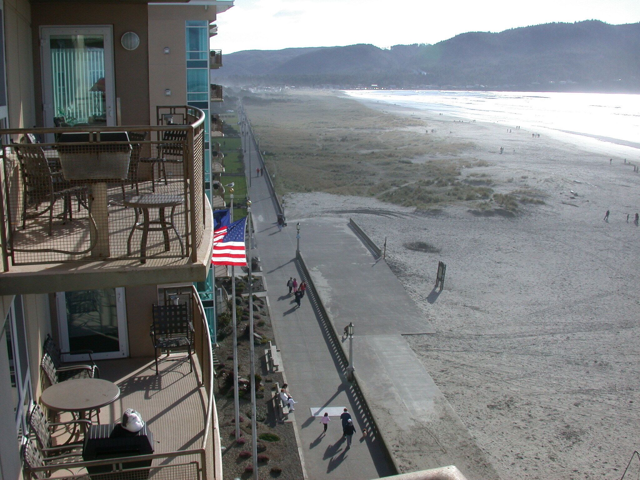Vista da praia a partir de uma varanda com mobiliário e uma bandeira americana.