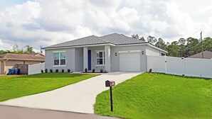 A single-story house with a grey roof, white exterior walls, and a front garage.