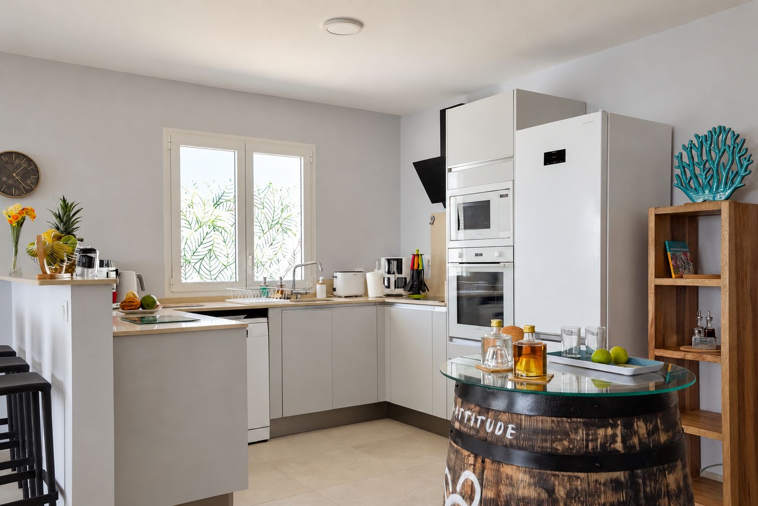 A modern kitchen with white cabinetry, a built-in microwave, oven, and a glass island with a bar stool.